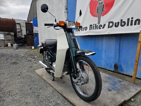 Front view of the Honda Super Cub C50, highlighting the round headlight, handlebars, and mirrors.